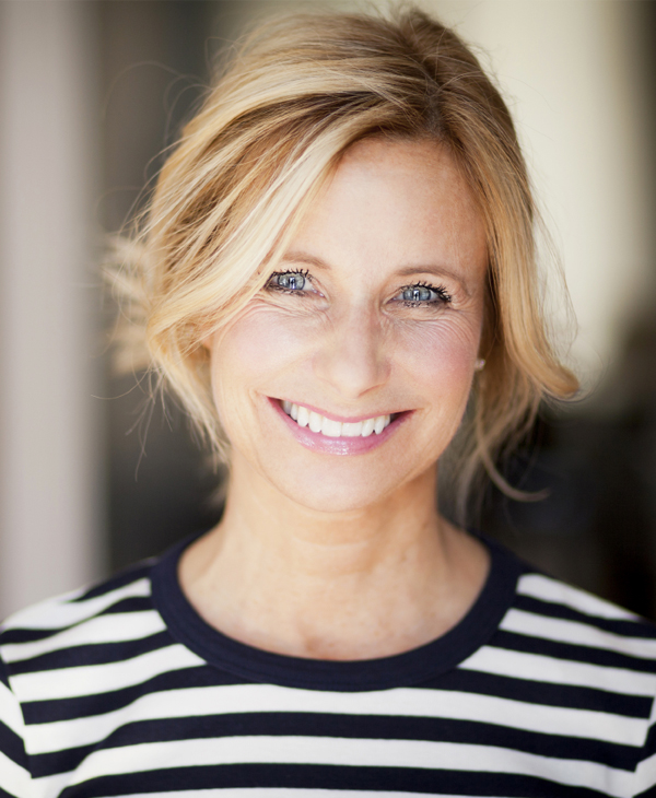 Woman smiling at camera wearing striped shirt in professional headshot setting.