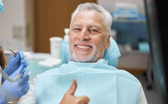 Senior man giving thumbs up in dental chair at Parkway Smiles Dentistry office.