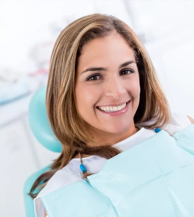 Woman smiling in dental chair wearing light blue bib at dental office.